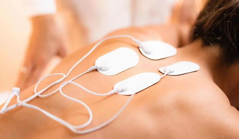 Upper Back Physical Therapy with TENS Electrode Pads, Transcutaneous Electrical Nerve Stimulation. Therapist Positioning Electrodes onto Patient's Upper Back